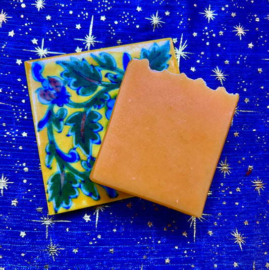 Orange soap on floral coaster against blue starry fabric